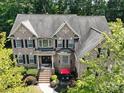Aerial view of a beautiful brick home with a well-maintained lawn, landscaping, and a red patio umbrella at 9913 Hazelview Dr, Charlotte, NC 28277