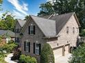 Side view of a brick home with an attached two-car garage and mature trees in the background at 9913 Hazelview Dr, Charlotte, NC 28277