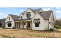 Charming two-story farmhouse with a covered porch, black window accents and well manicured landscaping at 111 Monbo Meadows Ln, Statesville, NC 28677