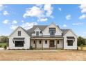 Beautiful two-story farmhouse with a covered porch, black window accents and well manicured landscaping at 111 Monbo Meadows Ln, Statesville, NC 28677