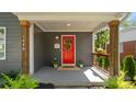 Inviting front porch featuring a vibrant red door with wreath, planters, and gray painted concrete at 1446 Downs Ave, Charlotte, NC 28205