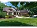 Beautiful brick home featuring lush landscaping, inviting walkway, and mature trees at 1500 Tarrington Way, Wesley Chapel, NC 28079