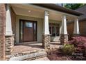 Inviting covered porch with stone columns, brick accents, and a stylish front door at 1500 Tarrington Way, Wesley Chapel, NC 28079