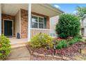 Close-up of a cozy front porch with stone accents, a white railing, and a charming landscaped garden at 1911 Savannah Hills Dr, Matthews, NC 28105