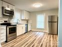 Modern kitchen featuring stainless steel appliances, ample cabinet space, and new wood flooring at 216 N Vance St, Gastonia, NC 28052