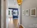 Inviting hallway featuring hardwood floors, elegant lighting, neutral paint and framed artwork, leading to an open living space at 229 N Church St # 204, Charlotte, NC 28202