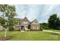 Charming stone-accented home with a manicured lawn and a circular driveway, nestled amongst mature trees at 2414 Madeira Cir, Waxhaw, NC 28173