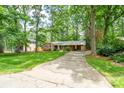 View of the home showing the driveway leading to the residence surrounded by lush trees at 403 Cherrywood Ln, Albemarle, NC 28001