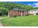 Brick home featuring an attached garage, well-kept lawn, and mature trees at 5633 Mallard S Dr, Charlotte, NC 28227