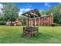 A well in the front yard sits in front of a charming two-story red brick home at 5633 Mallard S Dr, Charlotte, NC 28227