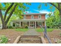 Inviting two-story brick home with a full front porch, complemented by mature trees and lush landscaping at 634 E Center Ave, Mooresville, NC 28115