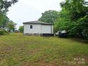 A view of the backyard showcasing a house with white siding, a truck, and a grassy lawn. Ready to be renovated at 720 Mutual Rd, Gastonia, NC 28052