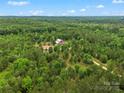 Expansive aerial view highlighting a serene rural property with a red barn-style house nestled in a dense forest at 925 Hamilton Rd, Chester, SC 29706