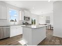 Modern kitchen with stainless steel appliances, kitchen island, white cabinets and light-filled adjacent dining area at 1433 Harleston St, Indian Trail, NC 28079