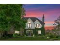 Beautiful ivy-covered Tudor-style home with stone details under a colorful sunset sky at 1550 Queens W Rd, Charlotte, NC 28207