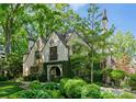 A charming Tudor-style home with stone and ivy accents nestled amongst mature trees at 1550 Queens W Rd, Charlotte, NC 28207