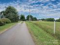 Scenic driveway leading to the property with a farm and tower on a verdant lawn under a blue sky at 269 Johnson Dairy Rd, Mooresville, NC 28115