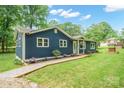Side view of blue house featuring attractive landscaping and a charming well at 327 Holly Dr, Mount Holly, NC 28120