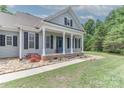 Inviting front porch with white pillars, brick accents, and a blue door, leading to a well-maintained yard at 3709 Creek Ridge Dr, Denver, NC 28037