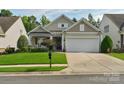 Inviting one-story home featuring a lush green lawn, an attached two-car garage, and manicured landscaping at 10405 Scotland Ave, Indian Land, SC 29707