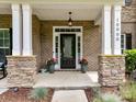 Inviting front porch with stylish stone columns, a black door, and decorative planters at 10800 Alabaster Dr, Davidson, NC 28036