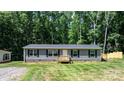 A single-story home features gray siding, blue shutters, and a small wooden porch, surrounded by a well-kept lawn at 110 Lambert Ln, Statesville, NC 28677