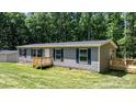 Welcoming home with gray siding, complemented by a wooden porch and lush green lawn; peaceful and inviting at 110 Lambert Ln, Statesville, NC 28677