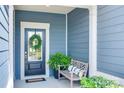Inviting front porch features a bench, potted plant, and a wreath on the blue front door at 1636 Red Leaf Dr, Fort Mill, SC 29715