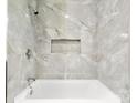 Elegant bathroom featuring stylish marble tiling, a sleek bathtub, and a convenient recessed shelf at 316 Fulton St, Kings Mountain, NC 28086
