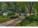 Beautiful exterior with mature trees, lush landscaping, driveway, and a painted, yellow front door at 331 Glen Oaks Rd, Charlotte, NC 28270