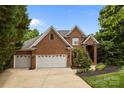 Charming brick home featuring a well-manicured lawn, mature trees, and a three car attached garage at 10317 Clubhouse View Ln, Mint Hill, NC 28227