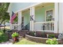 Detailed view of the front porch with an American flag, rocking chair, and landscaped flower bed at 186 Gresham Ln, Mooresville, NC 28117
