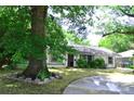 Home's exterior featuring a green lawn and a curved driveway, surrounded by mature trees at 2000 Tyvola Rd, Charlotte, NC 28210