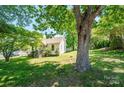 The front of the white house has big trees with green leaves and a lush green lawn at 3042 N Oxford St, Claremont, NC 28610