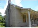 Tan home featuring a brick chimney, rain gutters, and a covered porch area at 418 W Cemetery St, Salisbury, NC 28144