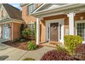 Inviting front porch with brick columns, a wreath on the door, and tasteful landscaping at 6430 Stirling Ln, Indian Land, SC 29707