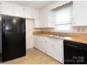 Functional kitchen with white cabinets, black appliances, and a stainless steel sink at 876 Stowe Ln, Gastonia, NC 28056