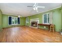 Inviting living room features green walls, hardwood floors, a ceiling fan and a brick fireplace for cozy gatherings at 9139 Robert Frost Ln, Charlotte, NC 28213