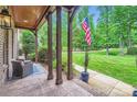 Cozy front porch showcasing stone flooring, wooden pillars, outdoor seating, and a view of the landscaped yard at 1056 James Madison Dr, Matthews, NC 28104