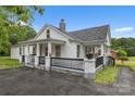 A bright white home has a cozy porch with black railings and a well manicured lawn at 111 E Church St, Stanley, NC 28164