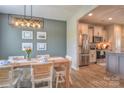 Open dining room adjacent to kitchen features a wood table and modern light fixture at 12531 Bryton Ridge Pkwy, Huntersville, NC 28078