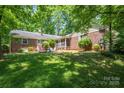 A spacious backyard with lush lawn, mature trees, brick home exterior, and a screened-in porch at 1503 Brentwood Dr, Newton, NC 28658