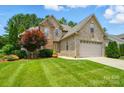 Beautiful two-story brick and stone home featuring a manicured lawn, mature trees, and an attached garage at 1705 Townsend Ln, Rock Hill, SC 29730