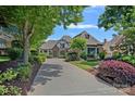 Attractive Tudor-style home featuring a long driveway and professional landscaping with mature trees and colorful bushes at 18718 Peninsula Cove Ln, Cornelius, NC 28031