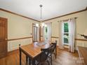 Dining room with natural light, wood floors, decorative chair rail, and classic chandelier above dining table at 2223 Jon Chris Dr, Harrisburg, NC 28075