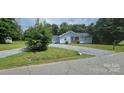 Cozy light-blue home with a gravel driveway and lush green lawn, offering a peaceful curb appeal at 2820 Bellhaven Cir, Charlotte, NC 28214