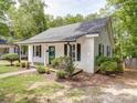 Exterior shot of a quaint house with a porch, lush greenery, and stone walkway, creating a welcoming curb appeal at 318 Chestnut Ave, Kannapolis, NC 28081