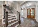 Elegant foyer featuring hardwood floors, a staircase, and a striking wood-framed doorway at 7435 Hammond Dr, Charlotte, NC 28215