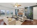 Cozy living room featuring a stone fireplace, modern decor, a ceiling fan, and large windows at 8406 Flint Hill Dr, Charlotte, NC 28273