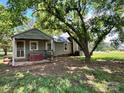 A charming home with a covered back porch is shaded by mature trees, providing an inviting outdoor space at 9401 Gold Hill Rd, Mount Pleasant, NC 28124